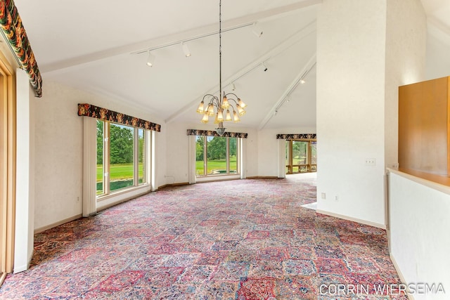 carpeted empty room with a chandelier, high vaulted ceiling, track lighting, and baseboards