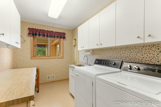 laundry room featuring a sink, visible vents, washer and dryer, cabinet space, and wallpapered walls