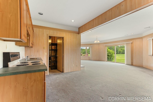 kitchen with carpet floors, dark countertops, open floor plan, and wooden walls