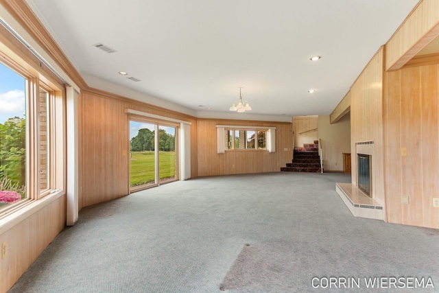 unfurnished living room featuring light colored carpet, a glass covered fireplace, visible vents, and wooden walls