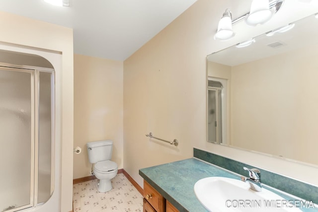 bathroom with toilet, a stall shower, vanity, and baseboards