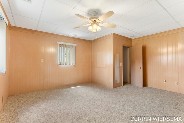 carpeted empty room with ceiling fan and wooden walls