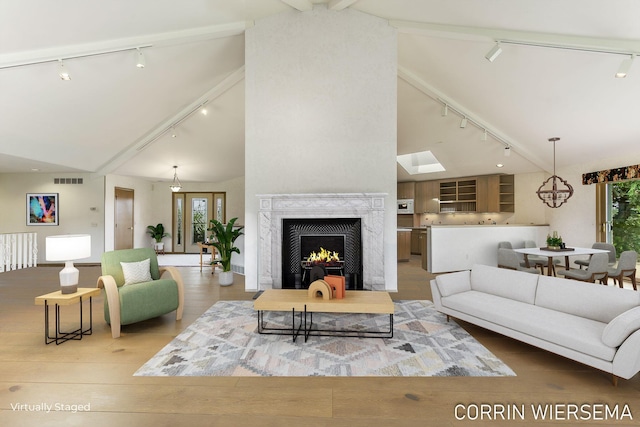 living area featuring track lighting, high vaulted ceiling, wood finished floors, a high end fireplace, and beamed ceiling