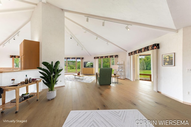 interior space with rail lighting, vaulted ceiling, baseboards, and hardwood / wood-style floors