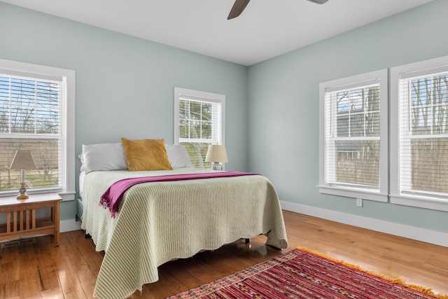 bedroom with wood finished floors, a ceiling fan, and baseboards