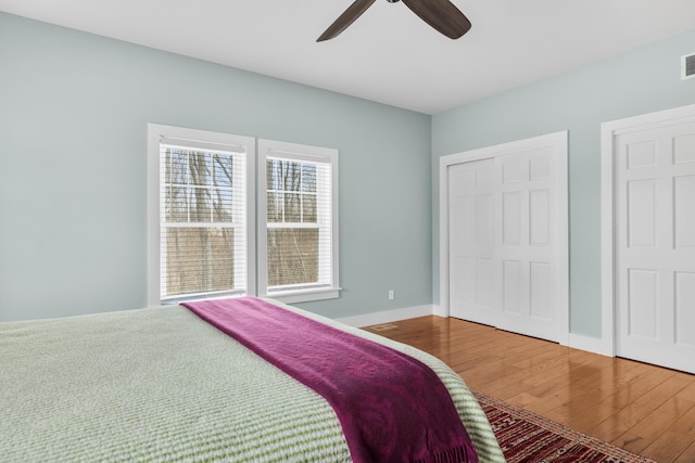 bedroom featuring a closet, visible vents, ceiling fan, wood finished floors, and baseboards