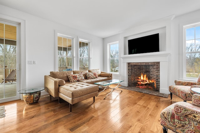 living area with a healthy amount of sunlight, light wood-style flooring, and a tile fireplace