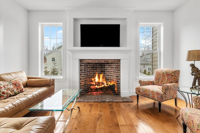 living room featuring a lit fireplace, hardwood / wood-style flooring, and a wealth of natural light