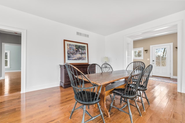 dining space with light wood-type flooring, visible vents, and baseboards