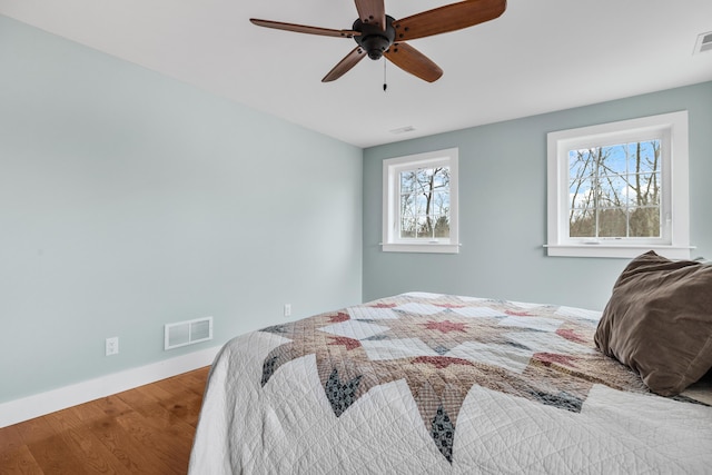 bedroom featuring visible vents, multiple windows, and wood finished floors