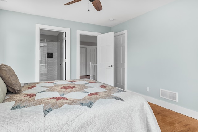 bedroom featuring visible vents, connected bathroom, ceiling fan, wood finished floors, and baseboards