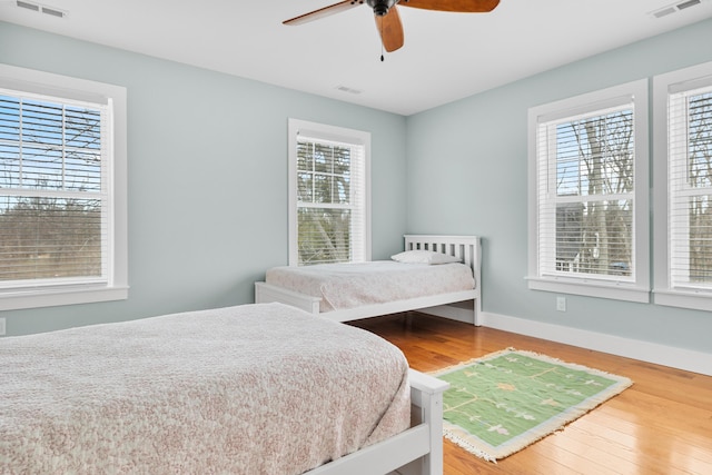 bedroom with baseboards, visible vents, and wood finished floors