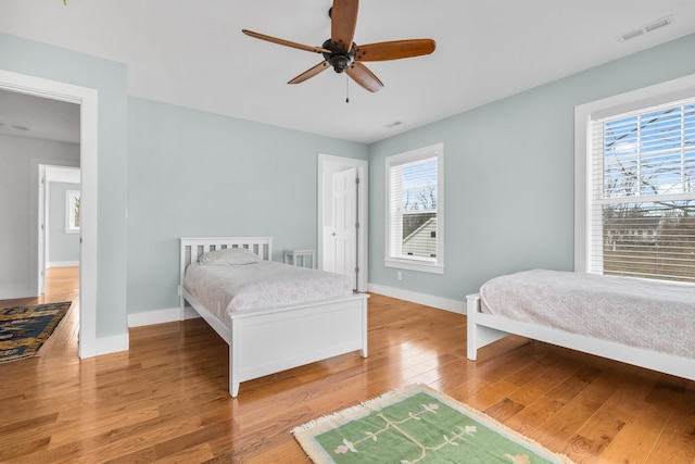 bedroom featuring baseboards, multiple windows, visible vents, and hardwood / wood-style floors