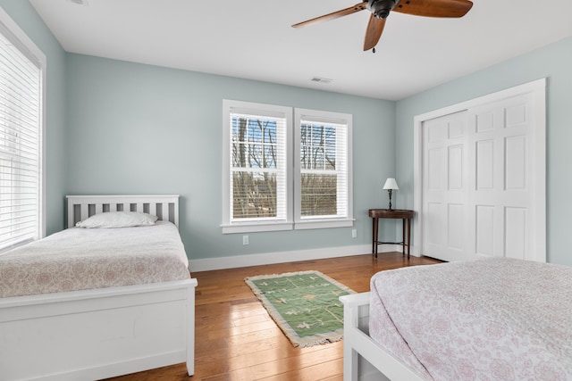 bedroom featuring a closet, visible vents, ceiling fan, wood finished floors, and baseboards