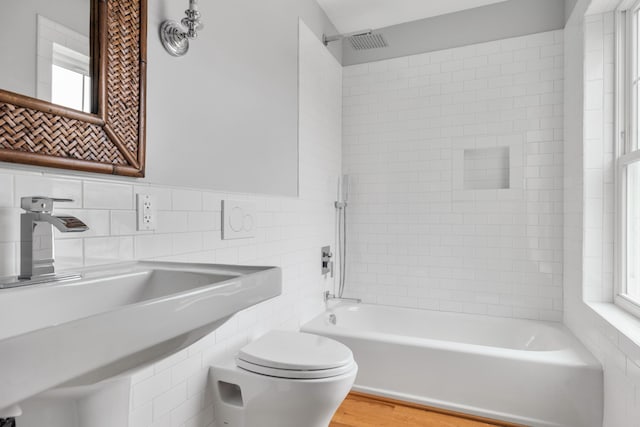 bathroom featuring tile walls, visible vents, toilet, a sink, and  shower combination