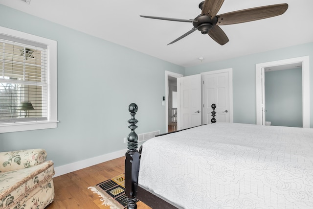 bedroom featuring a ceiling fan, visible vents, baseboards, and wood finished floors