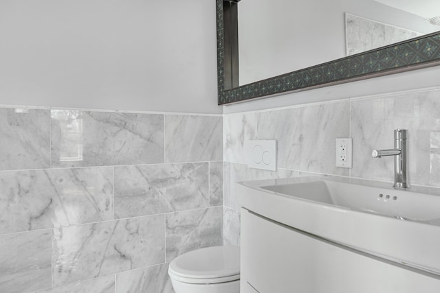 bathroom with tile walls, vanity, and toilet