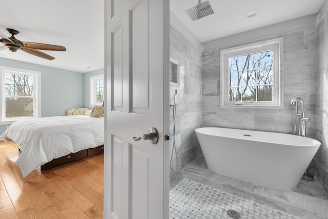 ensuite bathroom featuring ensuite bath, a freestanding tub, plenty of natural light, and wood finished floors