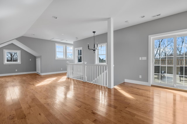 interior space with a chandelier, light wood-style flooring, lofted ceiling, and visible vents