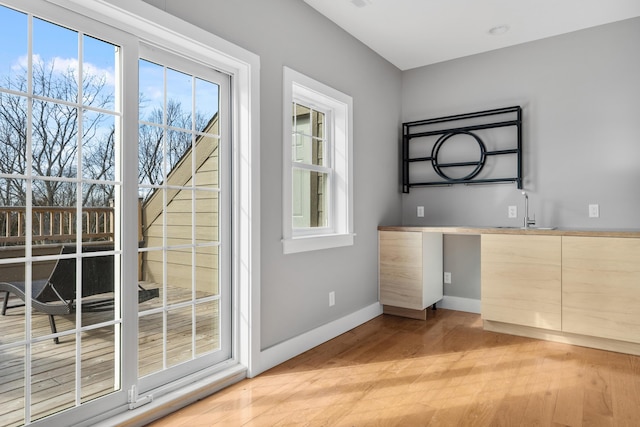 doorway featuring light wood-style floors, baseboards, and a sink