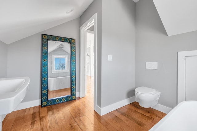 bathroom with lofted ceiling, baseboards, toilet, and wood finished floors