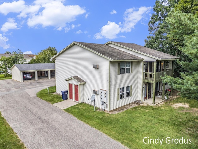 view of front of property featuring a shingled roof, a front yard, driveway, and a balcony