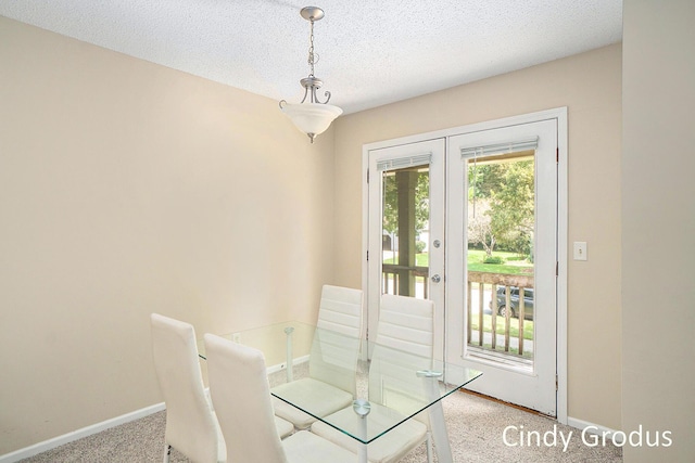 unfurnished dining area with a textured ceiling, french doors, carpet flooring, and baseboards