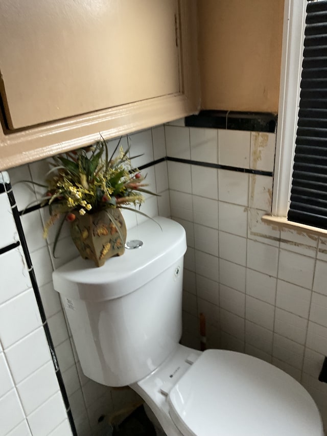 bathroom featuring toilet and tile walls