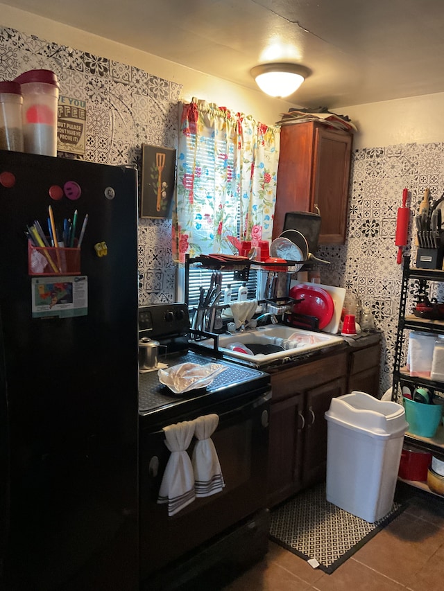 kitchen featuring a sink, black appliances, and tile patterned flooring