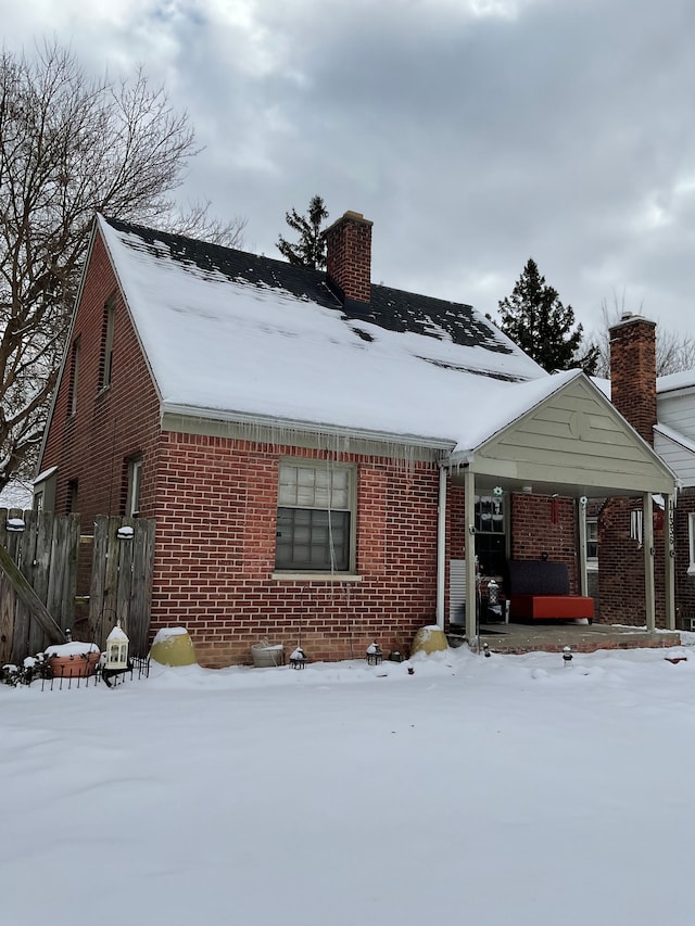 view of front of property with brick siding, a chimney, and fence