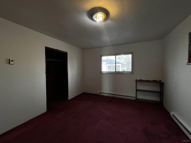 empty room featuring a baseboard heating unit and dark carpet