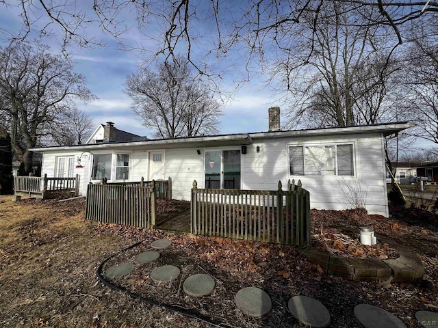 back of property featuring a chimney and a deck