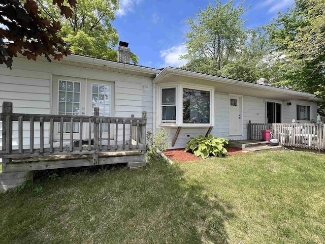 11698 Elm Park Dr, Manitou Beach, MI 49253 - view of front of house featuring a chimney, a front lawn, and a wooden deck