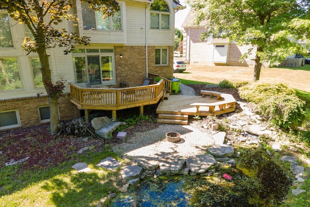 exterior space featuring a fire pit, a deck, and brick siding