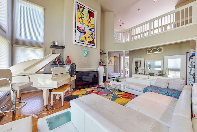 living area with ornate columns, a high ceiling, and wood finished floors