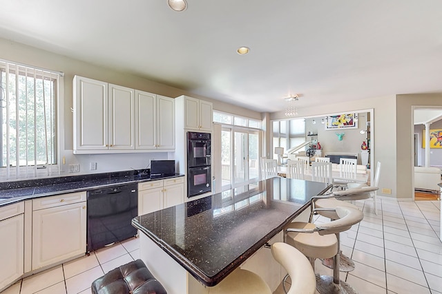 kitchen with black appliances, light tile patterned floors, and a breakfast bar