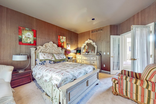 bedroom with light carpet and wood walls