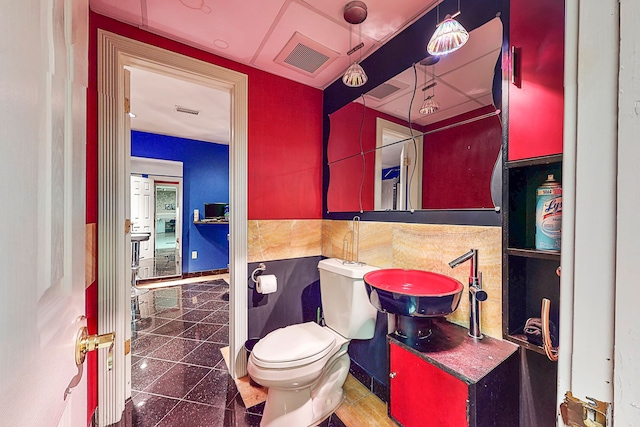 bathroom featuring toilet, granite finish floor, visible vents, and a sink