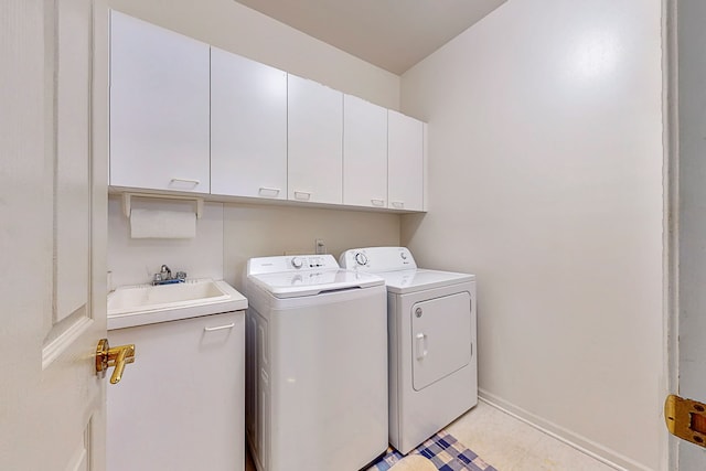 washroom featuring cabinet space, light tile patterned flooring, a sink, independent washer and dryer, and baseboards