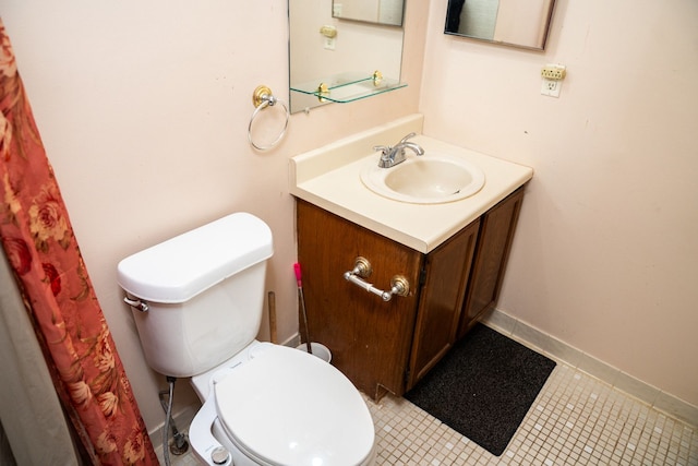 bathroom featuring toilet, tile patterned floors, baseboards, and vanity