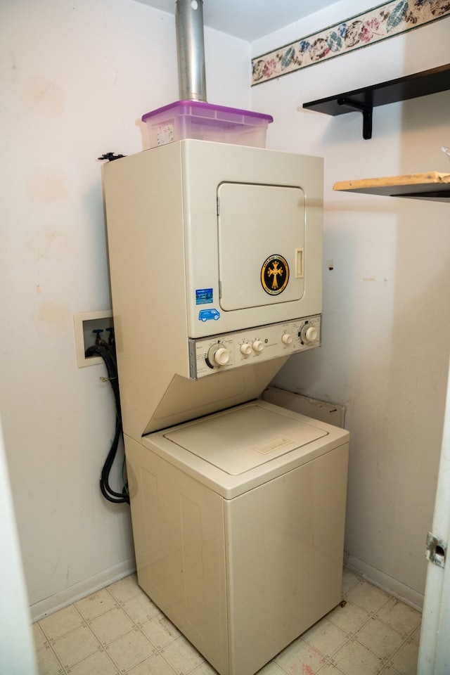 washroom featuring baseboards, light floors, laundry area, and stacked washer / drying machine