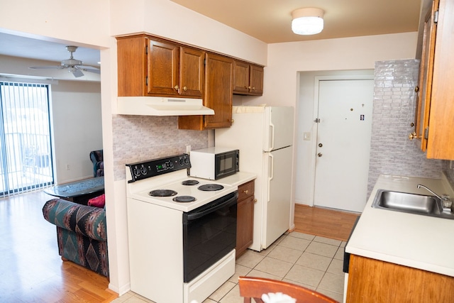 kitchen featuring light countertops, electric range, a sink, black microwave, and under cabinet range hood