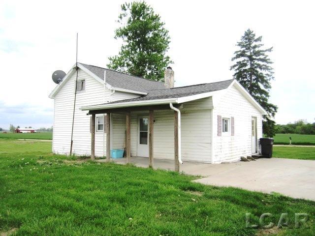 back of property with roof with shingles, a patio, a chimney, and a lawn