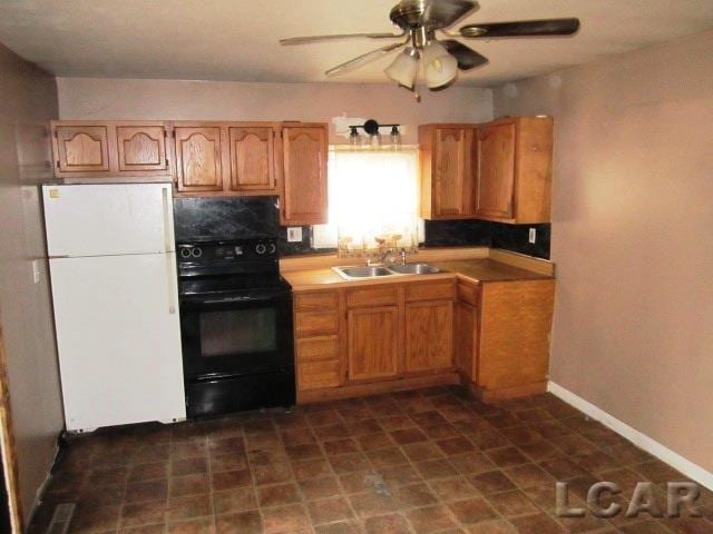 kitchen with ceiling fan, black range with electric cooktop, a sink, baseboards, and freestanding refrigerator