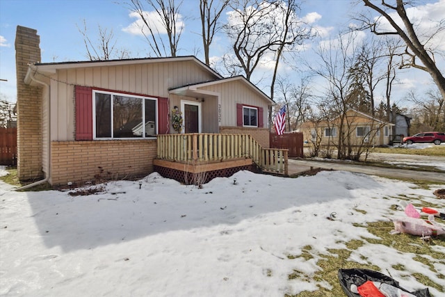 bungalow featuring brick siding, fence, and a chimney