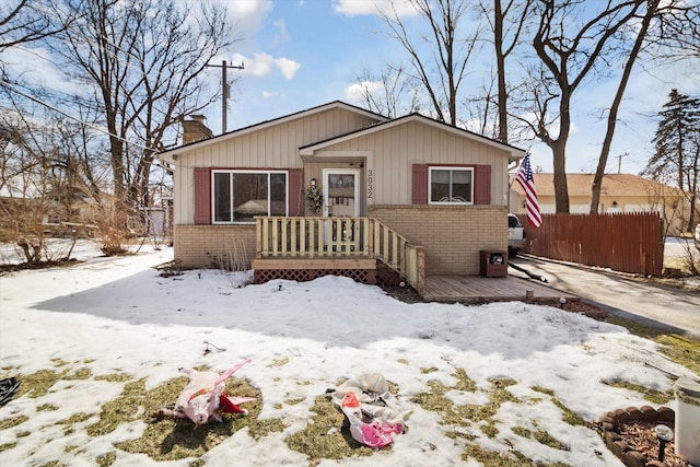 bungalow-style home with a deck, brick siding, fence, and a chimney