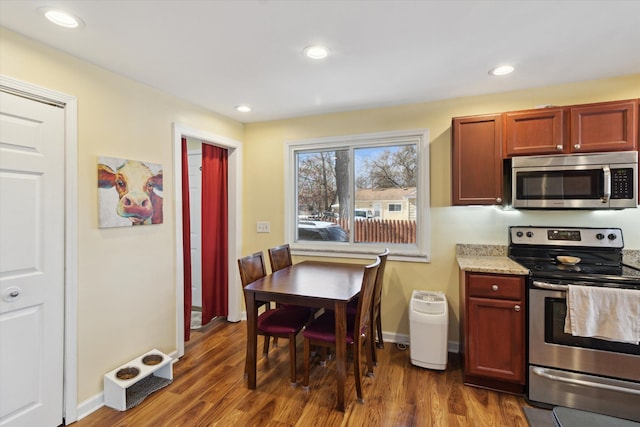 kitchen featuring reddish brown cabinets, baseboards, appliances with stainless steel finishes, dark wood-style flooring, and recessed lighting