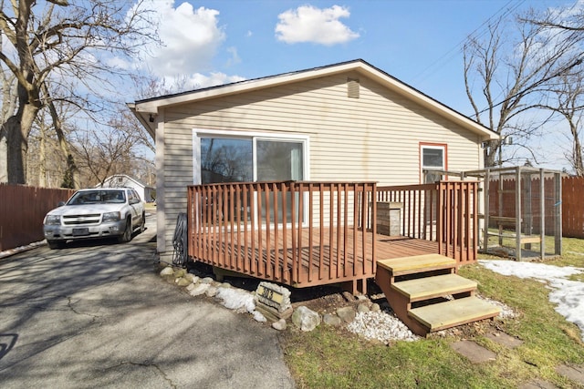 back of property with aphalt driveway, fence, and a wooden deck