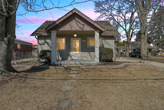 bungalow-style home featuring a porch and fence