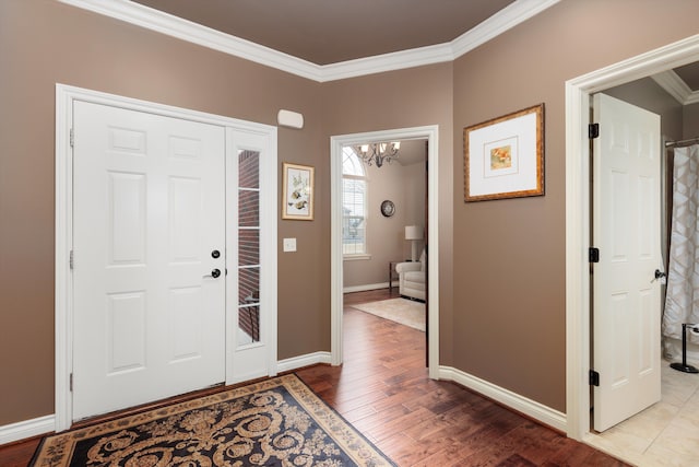 foyer with an inviting chandelier, baseboards, crown molding, and wood finished floors